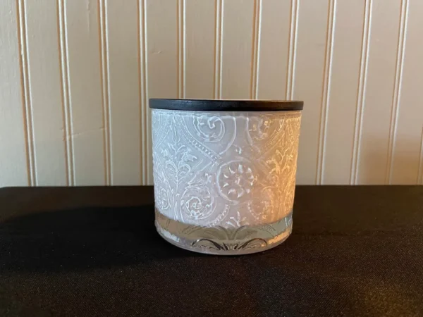 A white candle holder sitting on top of a table.