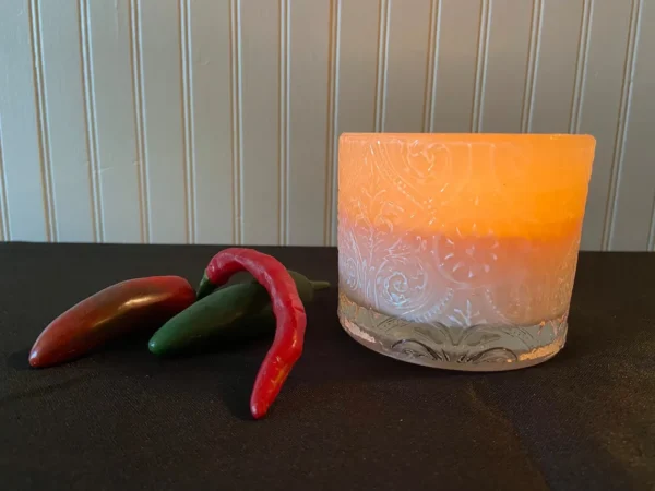 A candle and some peppers on the table