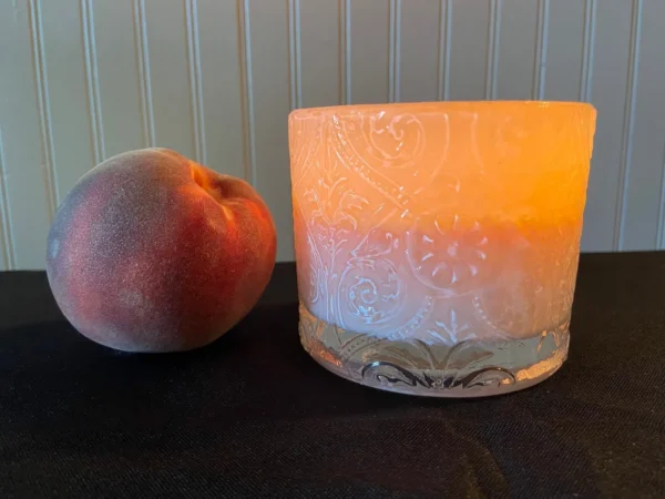 A peach and candle on the table