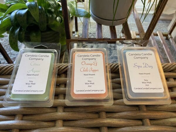 Three different scents of wax melts are sitting on a wicker basket.