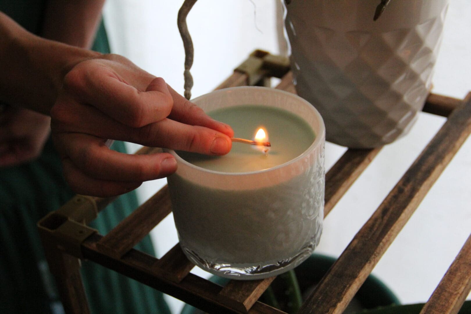 A person lighting a candle in a glass.